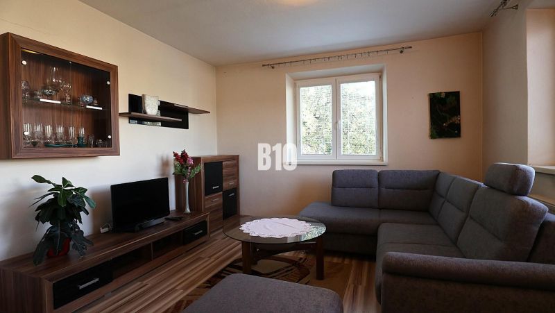 Wohnzimmer in einem Einfamilienhaus mit einem bequemen Sofa und einem Boden in Holzoptik.