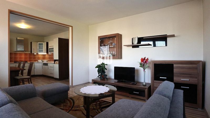 Wohnzimmer in einem Einfamilienhaus mit Blick auf die Küche und einem Boden in Holzoptik.