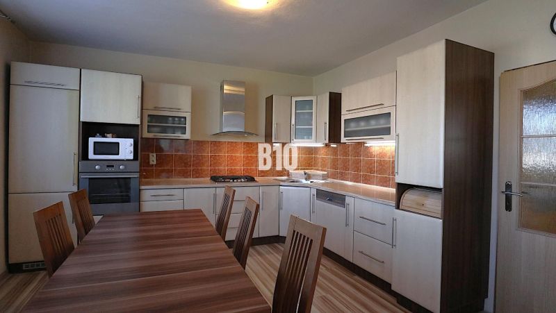 Küche in einem Einfamilienhaus mit Holzdekor und Geräten, mit geräumigem Esstisch.