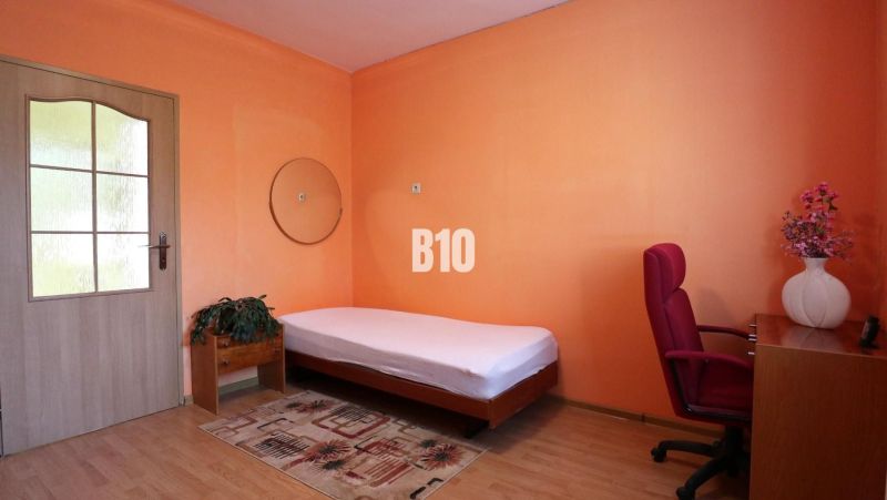 Ein Zimmer in einem Einfamilienhaus mit einem Bett, einem Schreibtisch und einem Boden mit Holzdekor.