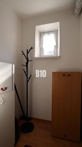 Ein kleiner Raum in einem Einfamilienhaus mit einer Garderobe und einem Schrank, Boden mit Holzdekor.