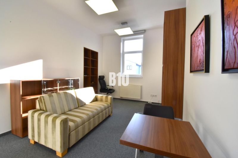 Büros mit gestreiftem Sofa, Tisch und Regal, einfaches Interieur.