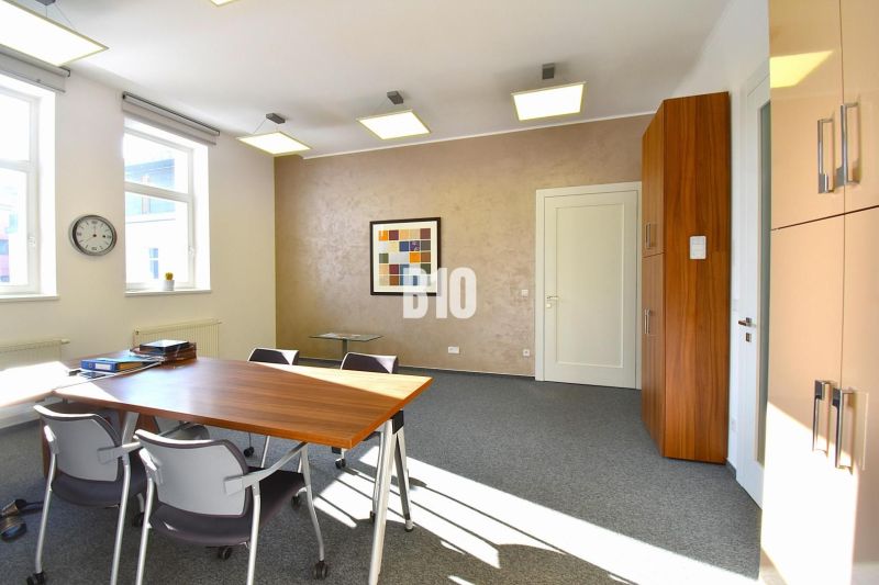 Ein Bürointerieur mit Teppichboden, Tisch, Stühlen und einem Wandbild.