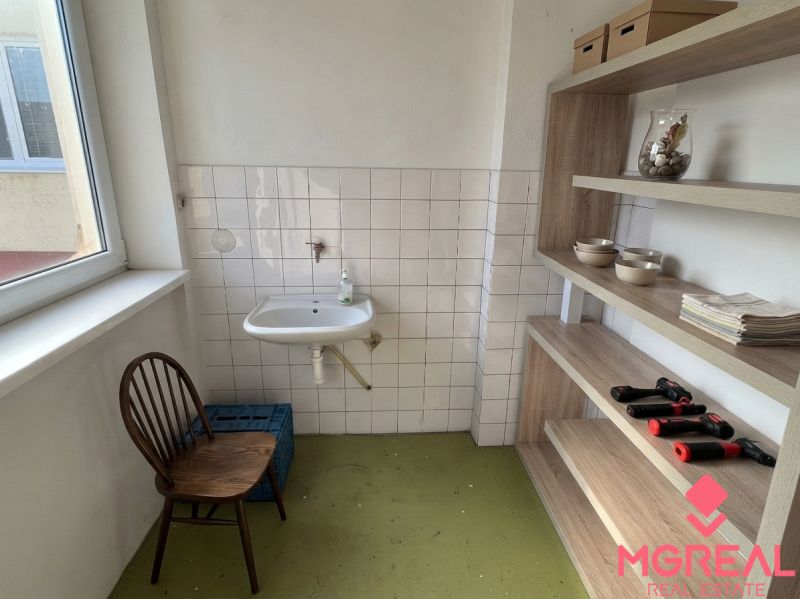 Badezimmer in einem Einfamilienhaus mit Waschbecken, Stuhl und Regalsystem.