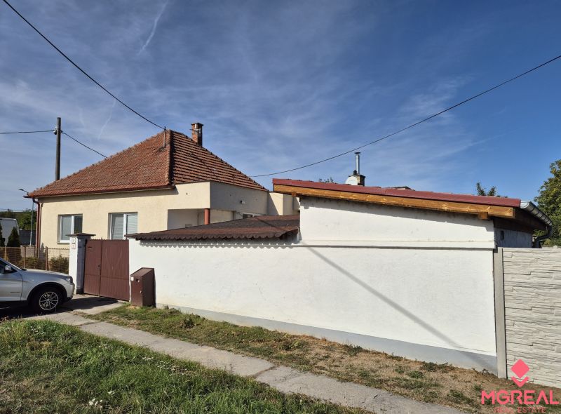 Ein Einfamilienhaus in Ludanice mit einem Schrägdach und einem Zaun, daneben ein geparktes Auto.