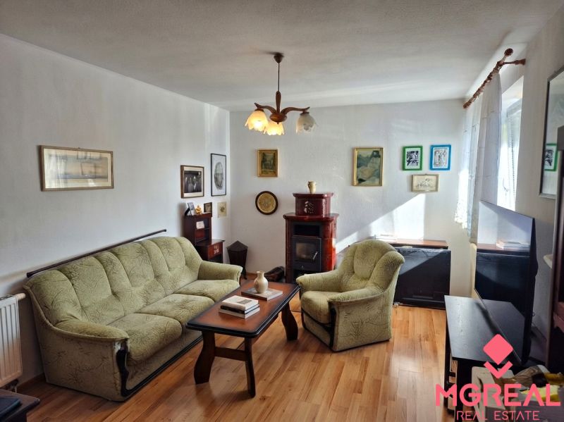 Wohnzimmer in einem Einfamilienhaus mit Sofa und Sessel, Boden mit Holzdekor.