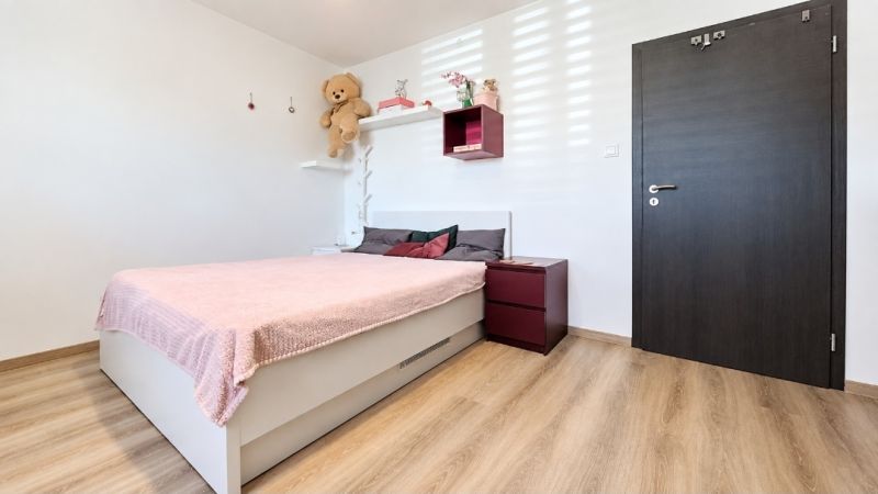 Schlafzimmer in einem Einfamilienhaus mit rosa Bett und Boden in Holzoptik.