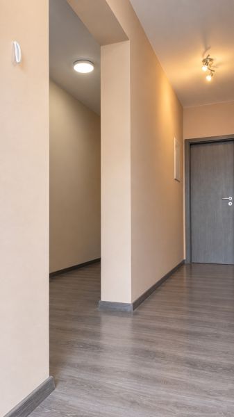 Ein Flur in einem Einfamilienhaus mit einem Boden in Holzoptik und neutralen Wänden.