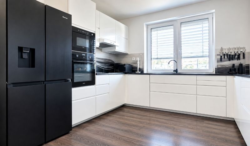 Küchenzeile mit schwarzen Geräten und einem Boden in Holzoptik in einem Einfamilienhaus.