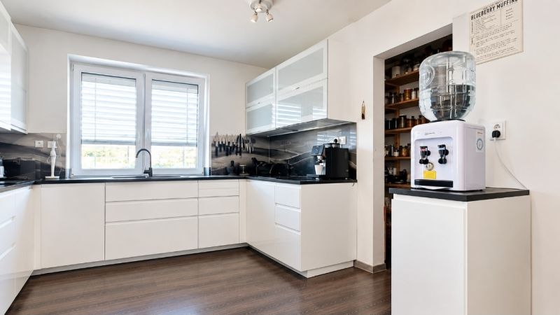 Küche in einem Einfamilienhaus mit weißen Schränken und einem Boden in Holzoptik.