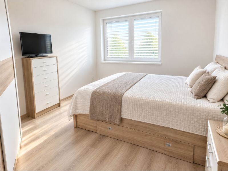 Helles Schlafzimmer mit Bett, Schrank und Holzboden in einem Einfamilienhaus.