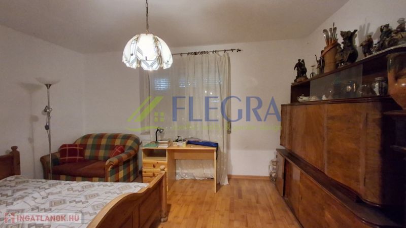 Ein Zimmer in einem Einfamilienhaus mit einem Einzelbett und einem Boden in Holzoptik.