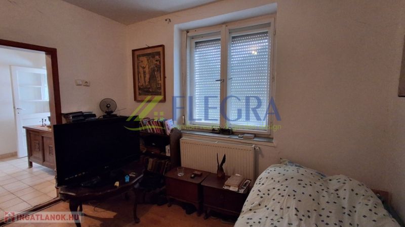 Ein Zimmer in einem Einfamilienhaus mit einem Bett, einem Fernseher und einer Kommode.