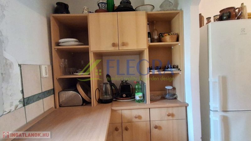Küchenschrank in einem Einfamilienhaus mit flachen Regalen und einem weißen Kühlschrank.