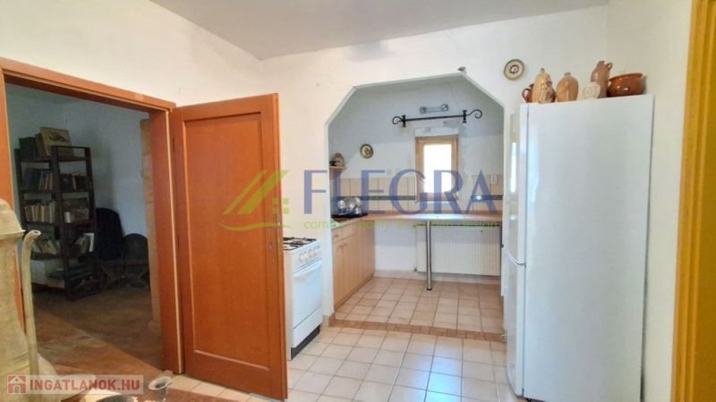 Eine Küche in einem Einfamilienhaus mit Keramikboden, einem Gasherd und einem weißen Kühlschrank.