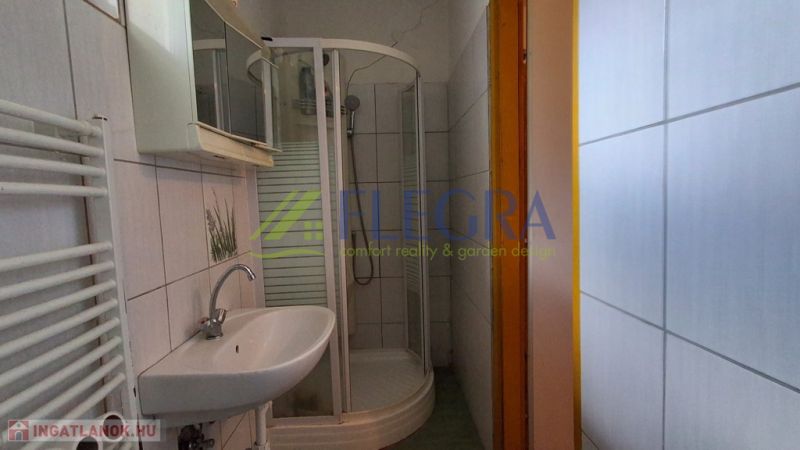Ein Badezimmer in einem Einfamilienhaus mit weißen Fliesen und einer Duschkabine.
