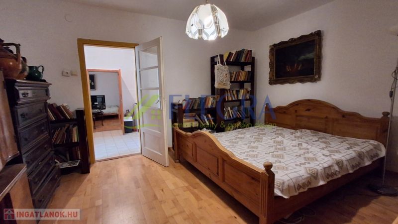 Ein Schlafzimmer in einem Einfamilienhaus mit einem Boden in Holzoptik, einem großen Bett und einer Lampe.