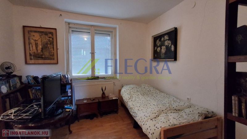 Ein Zimmer in einem Einfamilienhaus mit einem Bett, einem Fernseher und einem Boden in Holzoptik.