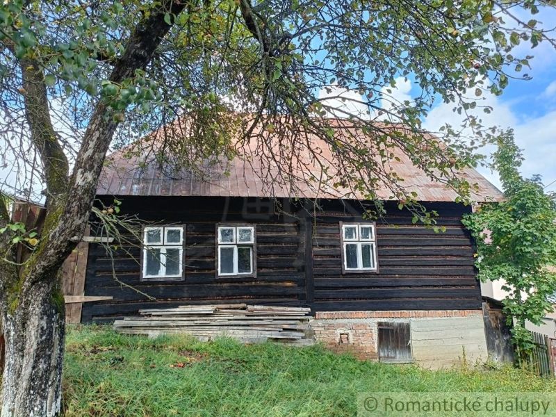 Rustikales Ferienhaus in Staškov, umgeben von Grün und blauem Himmel.