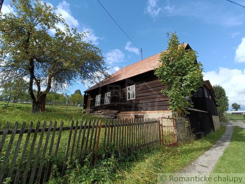 Eine Holzhütte in Staškov, umgeben von Grün und einem Zaun.