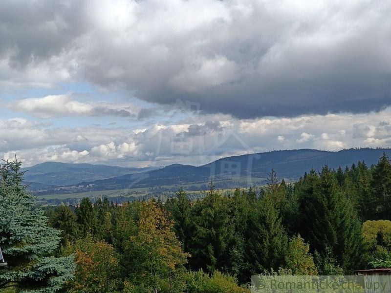 Blick von der Hütte in Staškov auf die hügelige Landschaft unter einem bewölkten Himmel.