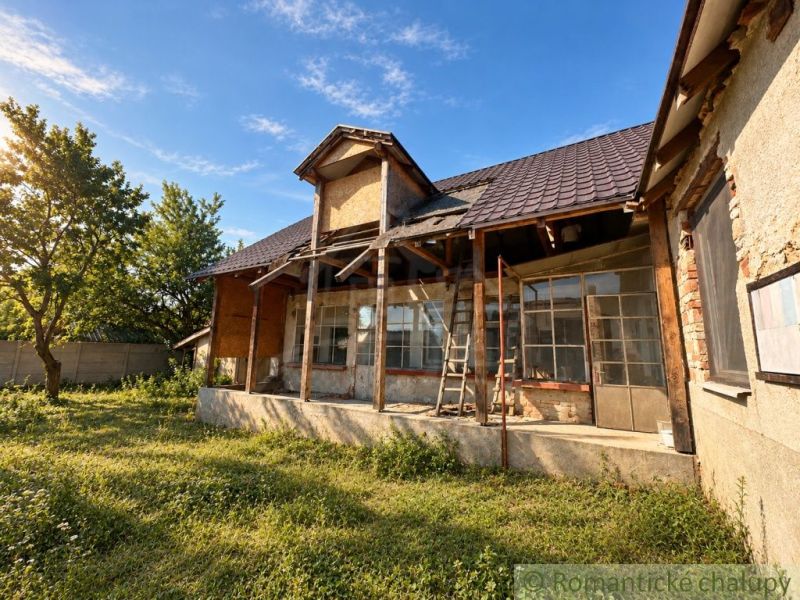 Ein Einfamilienhaus in Vištuk mit einer Veranda in Renovierung, umgeben von Grün und Bäumen.