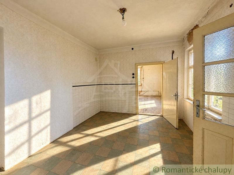 Innenraum eines Einfamilienhauses mit Fliesenboden und Licht, das durch die Fenster und offenen Türen dringt.