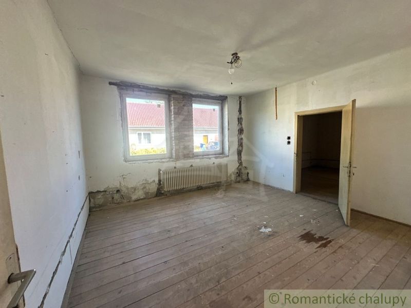 Ein Zimmer in einem Einfamilienhaus mit einem Holzboden-Dekor benötigt eine Renovierung.