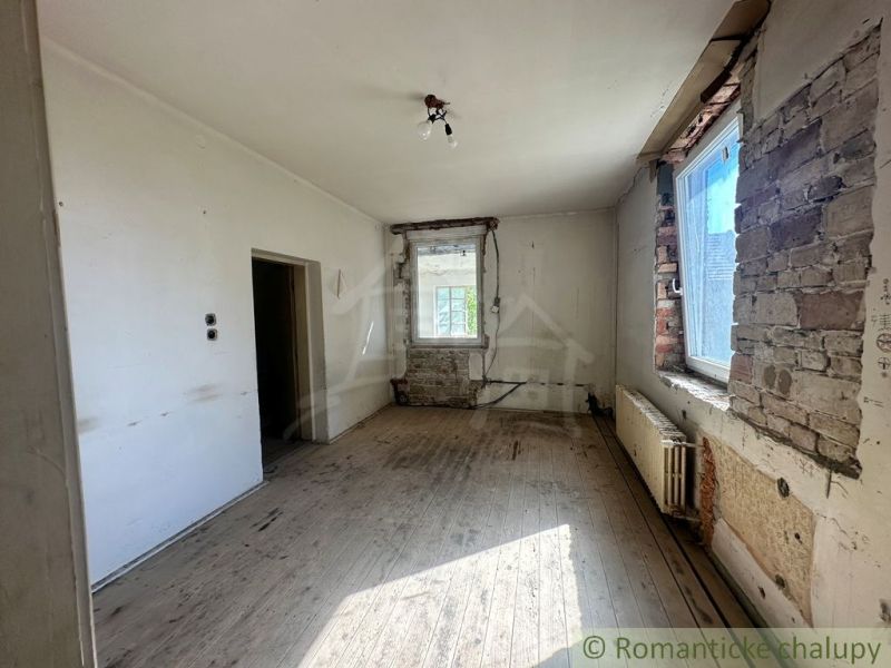 Ein abgenutzter Raum mit einem Holzboden, der auf eine Renovierung in einem Einfamilienhaus wartet.