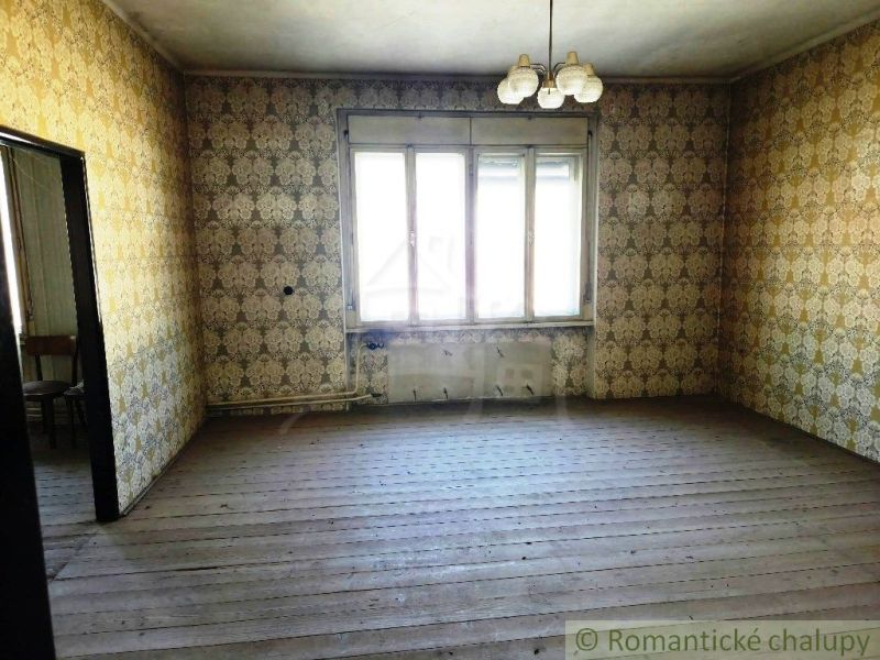 Ein Zimmer mit Tapeten und einem Holzboden, beleuchtet durch ein großes Fenster.
