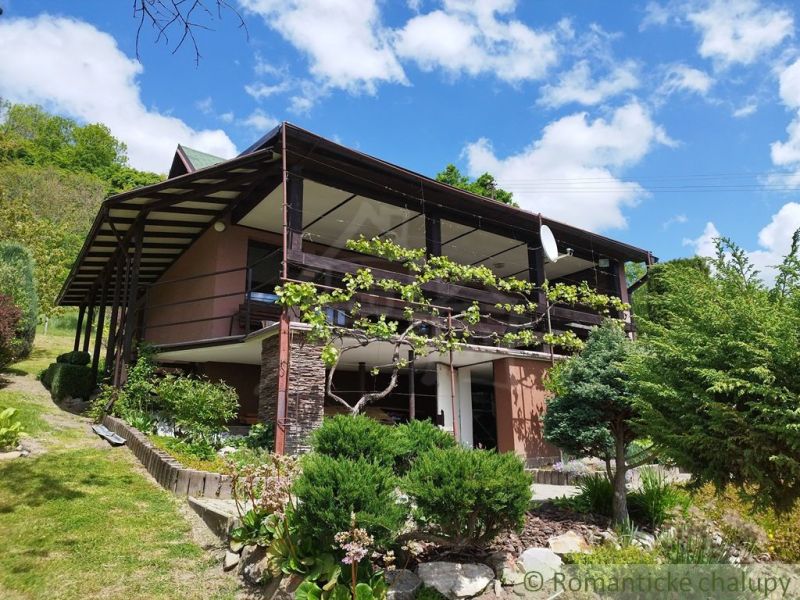 Ein Ferienhaus in Modrý Kameň mit Terrasse und gepflegtem Garten unter blauem Himmel.