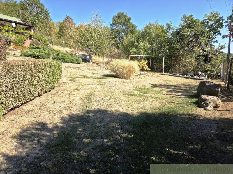 Eine Hütte in Modrý Kameň mit einem gepflegten Garten, Ziersträuchern und Bäumen.