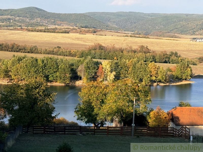 Ein See, umgeben von Herbstbäumen und Hügeln in den Gärten von Krupina.