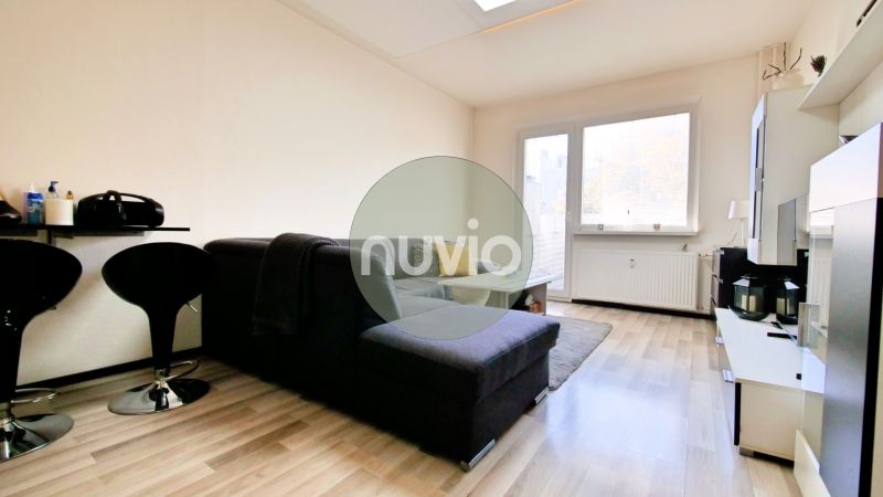 Wohnzimmer in einer Zweizimmerwohnung mit Holzboden und bequemer Couch.