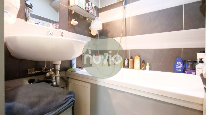 Badezimmer in einer 2-Zimmer-Wohnung mit Waschbecken und Badewanne, genutzter Stauraum für Kosmetik.