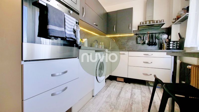 Küche mit weißen und grauen Schränken in einer 2-Zimmer-Wohnung, Boden mit Holzdekor.