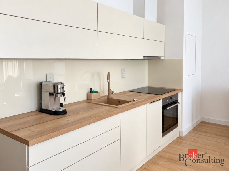 Küche in einer Einzimmerwohnung mit Holzdekorboden, cremefarbene Schränke, Kaffeemaschine.